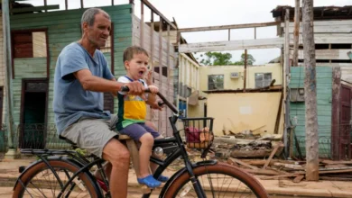 Residents cycle past homes damaged when Hurricane Rafael passed through Batabano, Cuba, on November 7