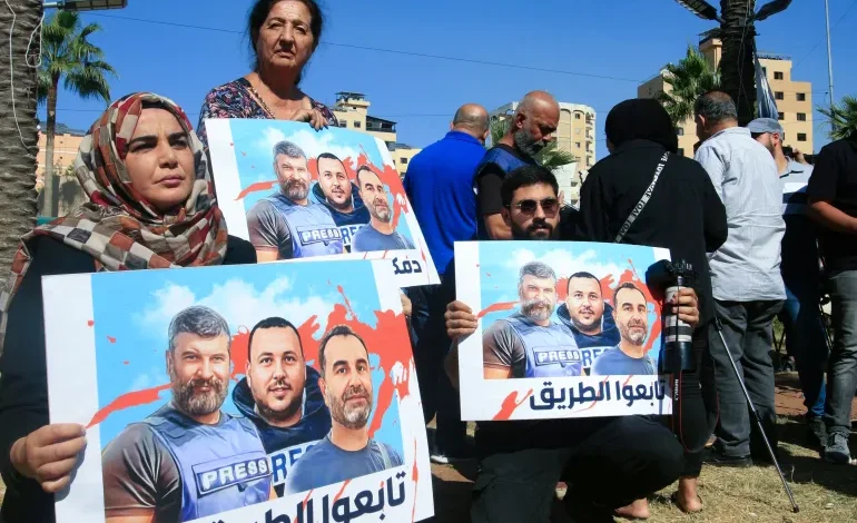 Media workers hold posters bearing the pictures of journalists killed in an Israeli strike in southern Lebanon, at a sit-in in Sidon, on October 26, 2024