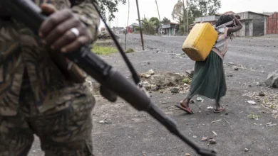 A child carrying water walks past Wazalendo forces fighting M23 rebels on patrol in Sake, DRC, on 31 August 2024.