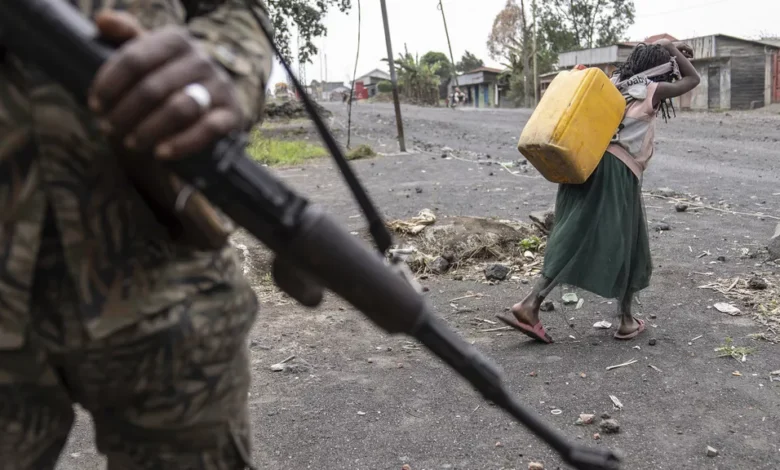 A child carrying water walks past Wazalendo forces fighting M23 rebels on patrol in Sake, DRC, on 31 August 2024.