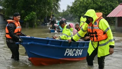 Malaysian police transport residents on a boat through floodwaters after heavy rain in Tumpa, Kelantan state, November 30, 2024