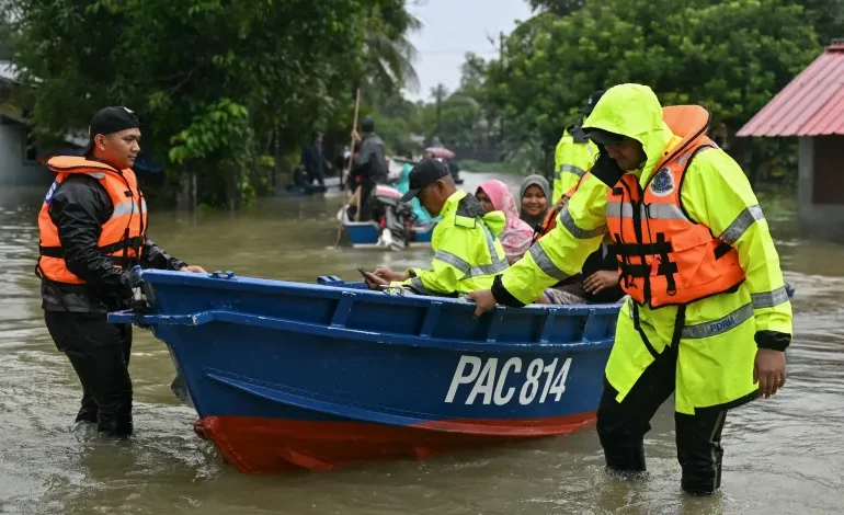 Malaysian police transport residents on a boat through floodwaters after heavy rain in Tumpa, Kelantan state, November 30, 2024